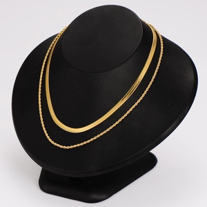 Flat herringbone and rope style gold stainless steel chains on a black display stand