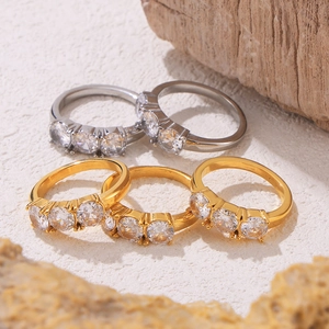 Three-stone zircon gold and silver titanium steel rings set on natural wood background