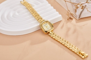 Detail of vintage gold women watch with rectangular dial on elegant white textured surface