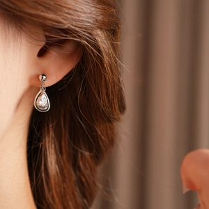 Close-up of sparkling zircon teardrop earrings worn by a model in silver finish