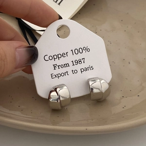 Detailed macro view of silver twisted hoop earrings made of 100% polished copper material