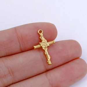 Golden rose cross pendant held between fingers to show detailed size and texture