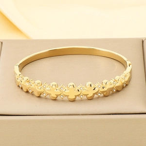 Close-up of gold clover knot bangle with white rhinestones on a jewelry display box