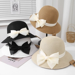 Détail de quatre chapeaux de paille colorés avec de grands nœuds élégants en tissu