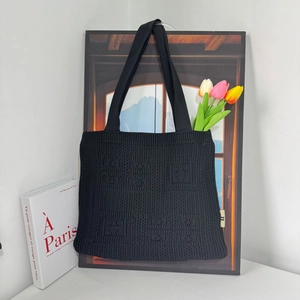 Detailed texture of black knit tote bag with geometric woven patterns and sturdy handles