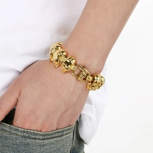 Close-up of a gold skull bracelet for men worn on a wrist with a casual denim style