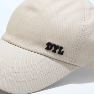 Close-up of DYL letter embroidery on beige cotton high ponytail baseball cap details