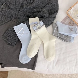 Détail de chaussettes en coton avec nœuds et bordure en dentelle en bleu et crème doux