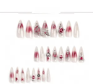 Détails d'ongles amandes longs avec dégradé rouge, papillons argentés et cristaux