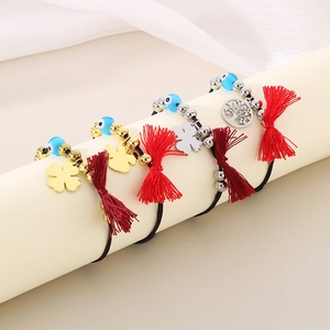 Detail of clover and tree of life charms on braided red tassel evil eye bracelets