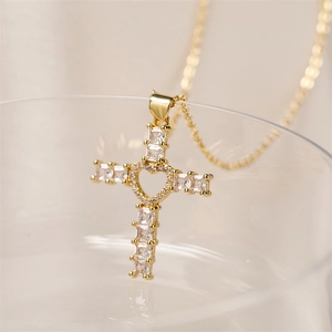 Macro shot of gold-plated cross pendant with heart cutout and sparkling square zircons