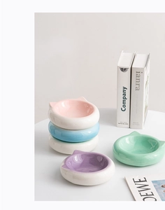 Close-up of ceramic cat ear shaped pet bowls in various soft macaron colors on a desk