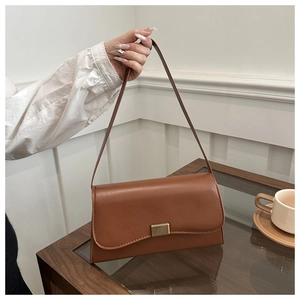 Detail of caramel leather shoulder bag with a textured gold metallic lock and flap closure