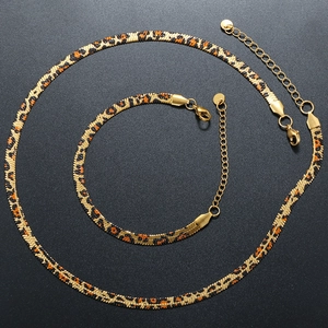 Detailed view of gold snake chain jewelry set with leopard print on black background