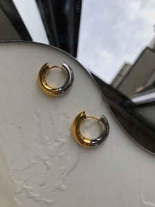 Detail of two-tone gold and silver chunky hoop earrings with high polish finish