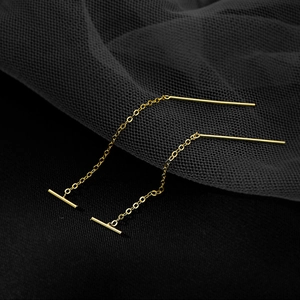 Macro shot of minimalist gold long tassel earrings with geometric bar and delicate O-chain