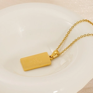Detailed close-up of 18K gold stainless steel zodiac rat pendant on a white ceramic plate