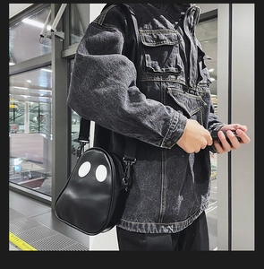 Ghost shaped PU leather crossbody bag worn by a model in a modern urban street setting