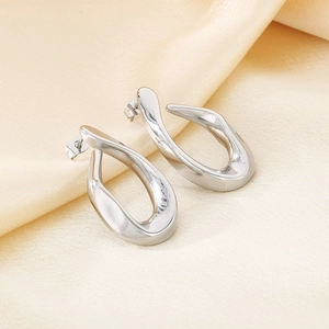 Detail of silver twisted teardrop earrings on elegant champagne silk background