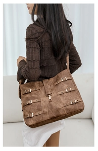 Detail of vintage brown suede tote bag with parallel metallic buckles and lobster clasp
