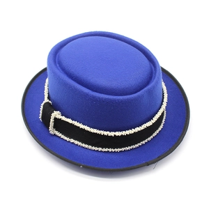 Detail of royal blue felt boater hat featuring a black ribbon with fine white bead trim