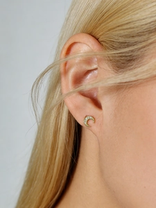 Detail view of gold crescent moon stud earrings with sparkling cubic zirconia on a model