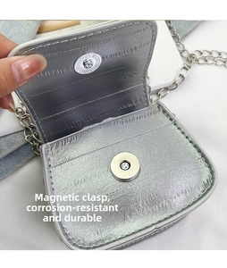 Macro shot of silver patent leather bag featuring a magnetic snap closure and metal chain