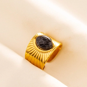 Detailed macro view of vintage gold ring with black oval stone and sunburst texture