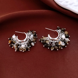 Detail of silver beaded tassel earrings with amber texture beads on red velvet fabric