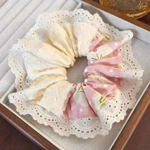 Detail of pink floral and yellow fabric scrunchie with lace edge in jewelry tray