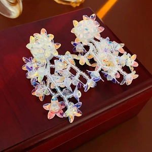 Macro shot of colorful iridescent beaded flower tassel earrings on a vintage wooden box