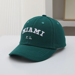 Close-up of white MIAMI embroidery on a forest green 6-panel cotton baseball cap