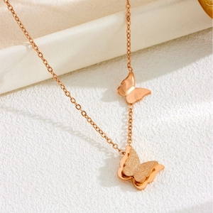 Elegant rose gold butterfly necklace with matte textured pendant on a white marble display
