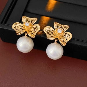 Close-up of vintage gold floral earrings with white pearls on a black jewelry box