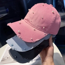 Detailed view of distressed baseball caps with pearls in pink, blue, and black colors