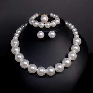 Detailed set of large white pearl necklace, bracelet and stud earrings on black display