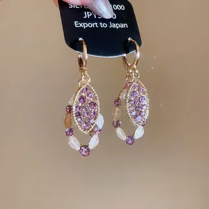 Elegant gold oval drop earrings featuring purple crystals and white beaded borders