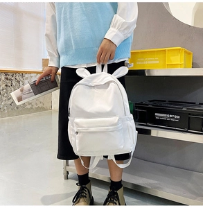 Close-up of white rabbit ear backpack detail with front zipper pocket and side water bottle pouch