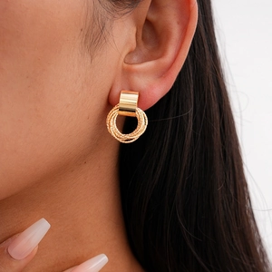 Golden stud earrings with multi-layered textured metal rings on a fashion model