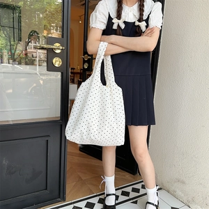 Polka dot canvas tote bag shown being carried by a model in a minimalist setting