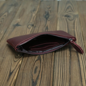 Macro shot of burgundy crazy horse leather wallet with zipper closure on wood surface