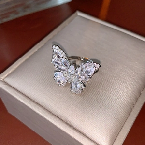 Bague papillon argentée avec zircons sur boîte à bijoux en velours beige, vue macro