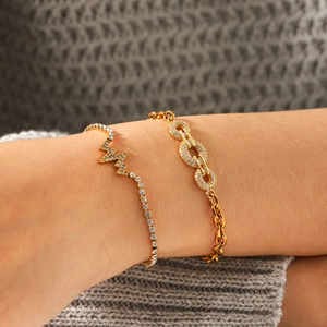 Women's gold stainless steel bracelet set with lightning zircon charms on gray sweater background