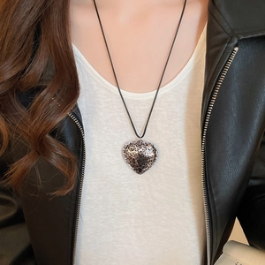 Close-up of heart-shaped leopard print pendant on a black cord necklace worn by model