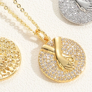 Close-up of interlocking hands pendant necklace with pavé cubic zirconia inlay detail
