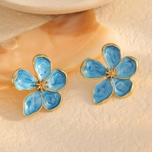 Detail of blue enamel flower earrings with gold metal petals and textured finish