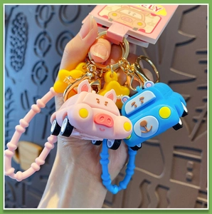 Detail of pink pig and blue bear cartoon car keychains with silicone wristbands