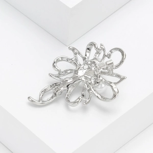Detail view of the silver flower brooch showing the secure metal pin back mechanism