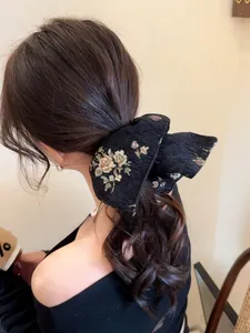 Detailed back view of a black jacquard hair scrunchie with colorful floral embroidery
