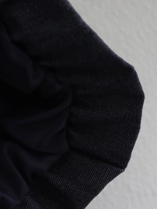Macro shot highlighting the deep blue denim fabric texture and sturdy weave of the jacket